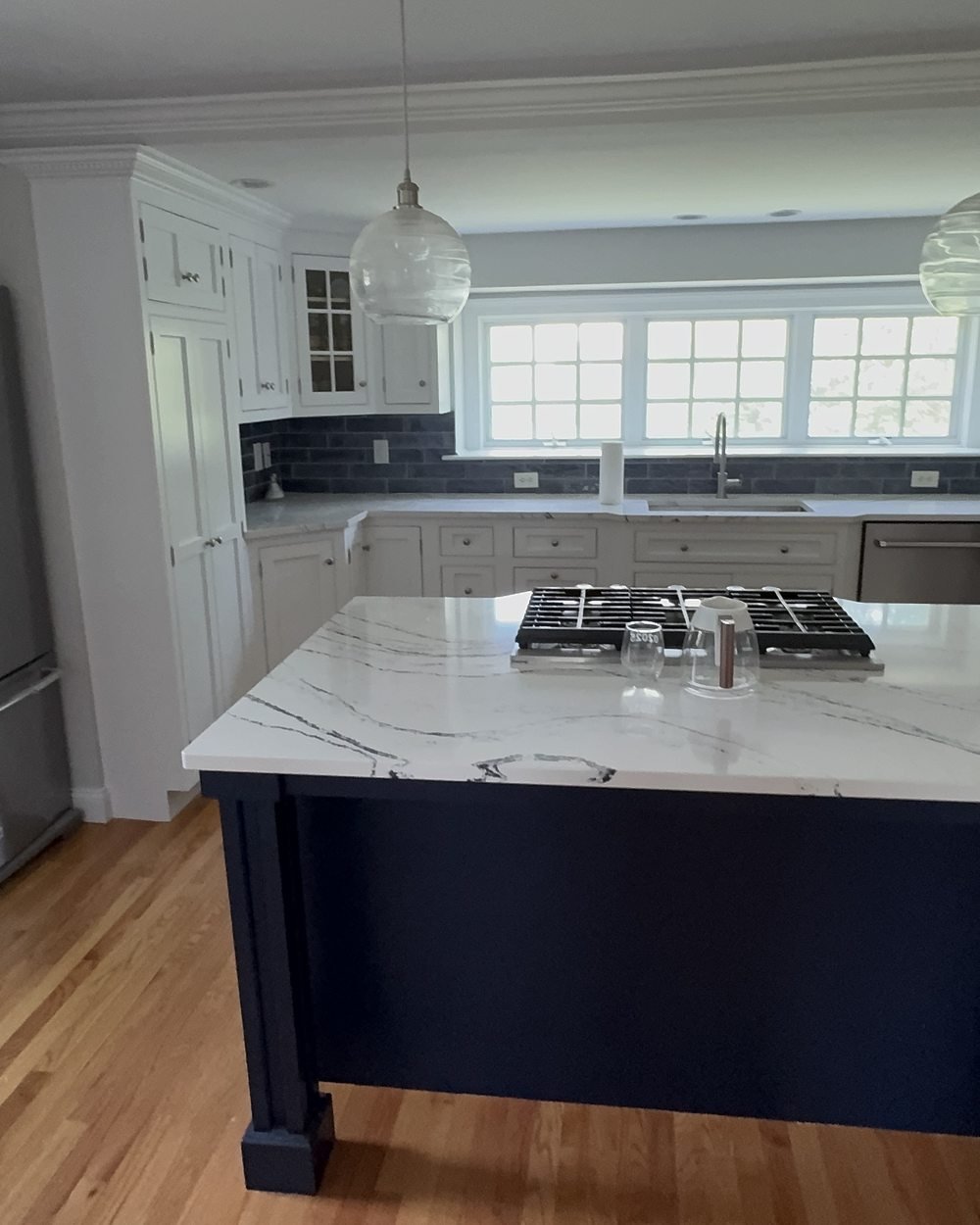 Front view of a custom kitchen with navy blue island, marble countertop and white cabinets painted by Painting Now