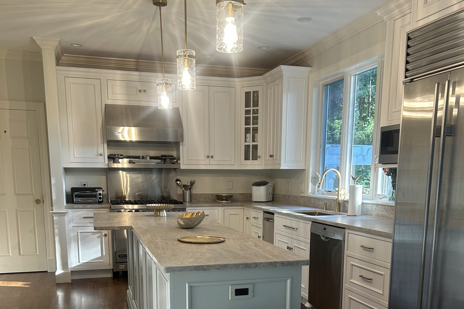 Wide view of the finished kitchen with a pale island and bright white cabinetry