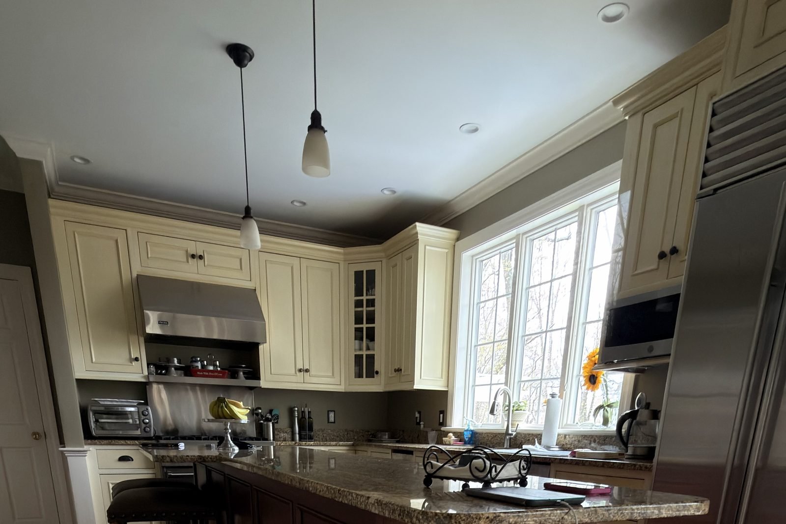 The same kitchen before refinishing with cream cabinets and olive walls
