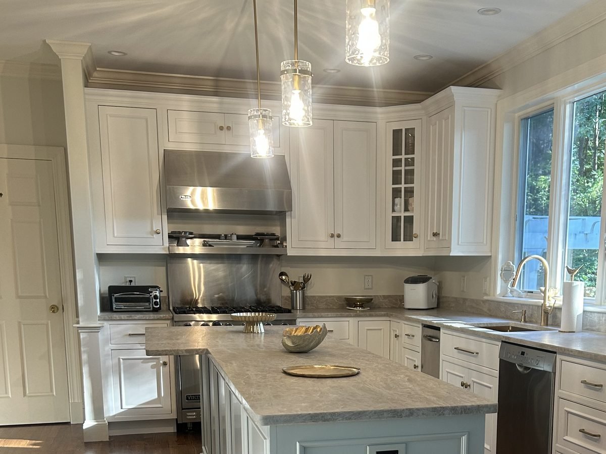 Kitchen island in soft blue with the full white cabinet run freshly finished
