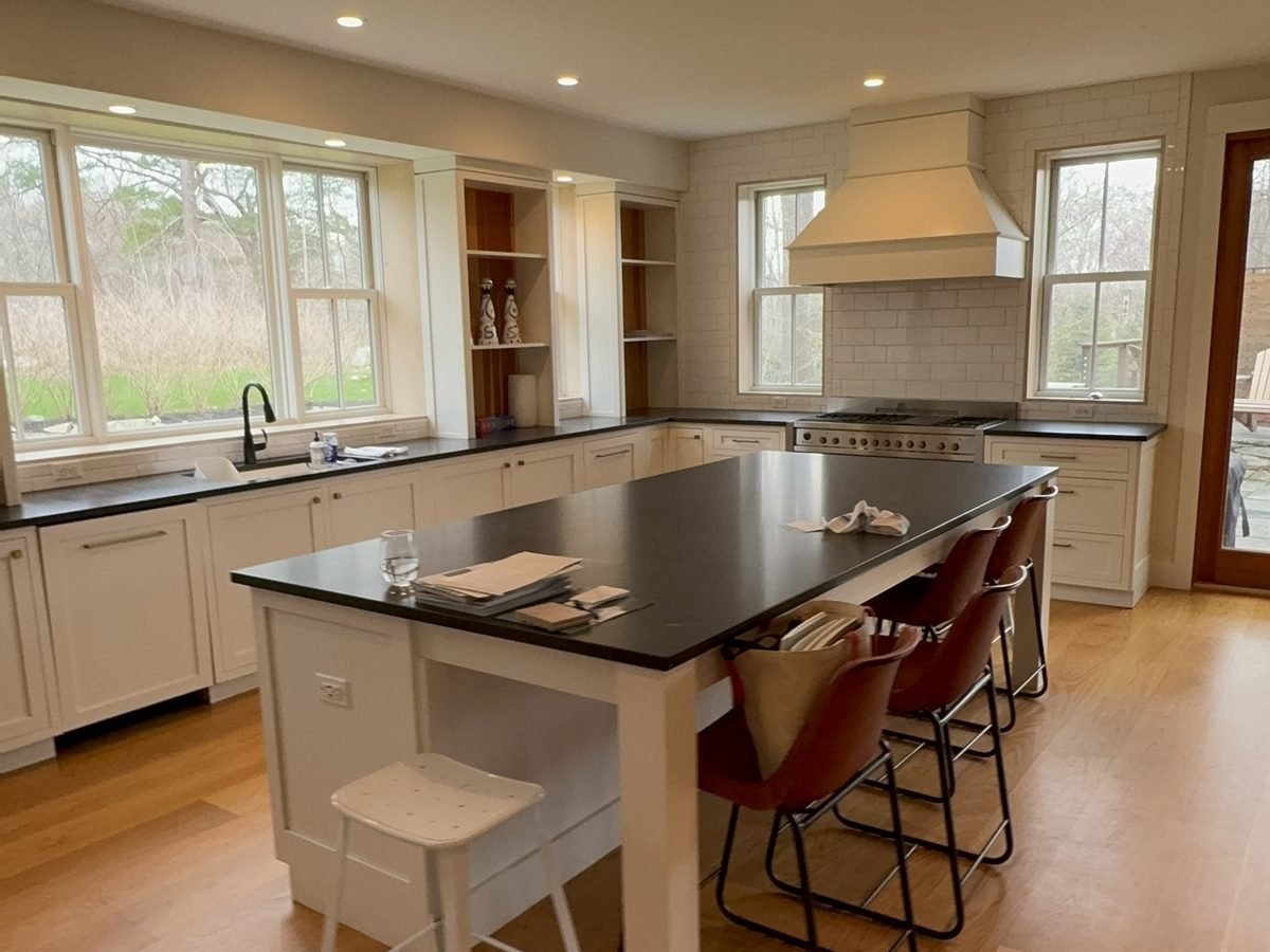 Kitchen with a plaster range hood, white cabinetry and a dark island