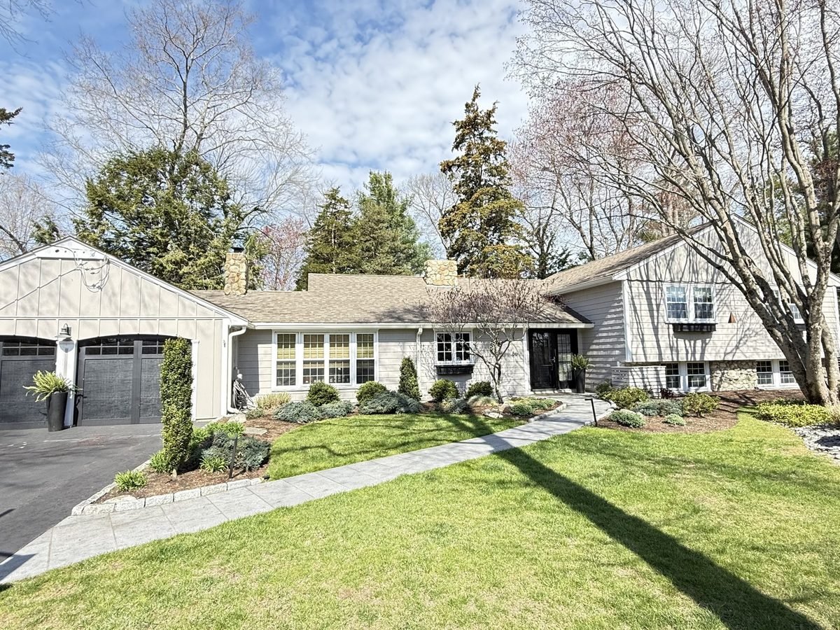Shingle style ranch home with white painted trim under a blue sky