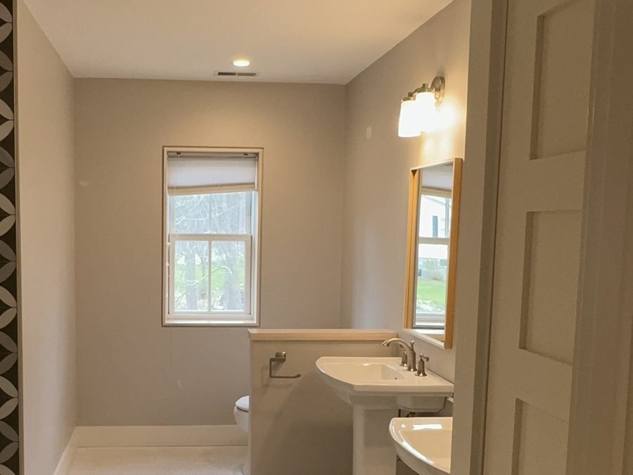 Freshly painted bathroom with soft greige walls, white trim and pedestal sinks