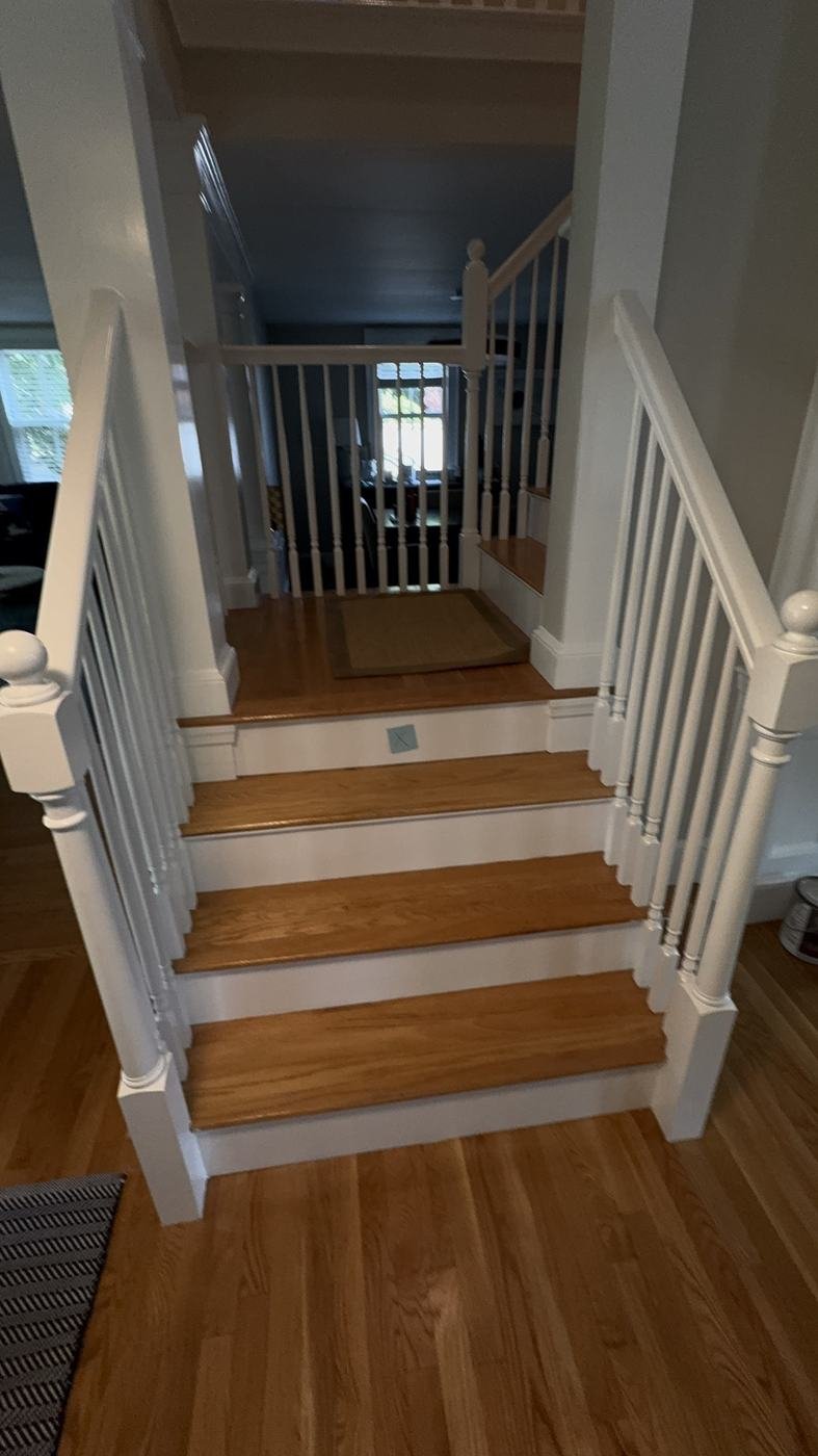 Staircase with freshly painted white balusters, risers and newel posts