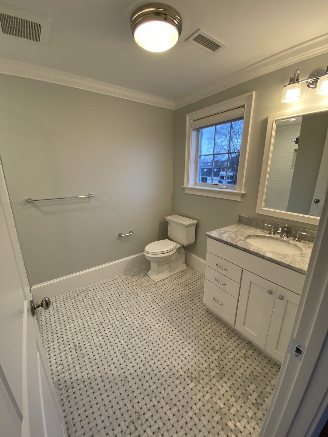 Bathroom with soft sage walls, crown molding and a white painted vanity