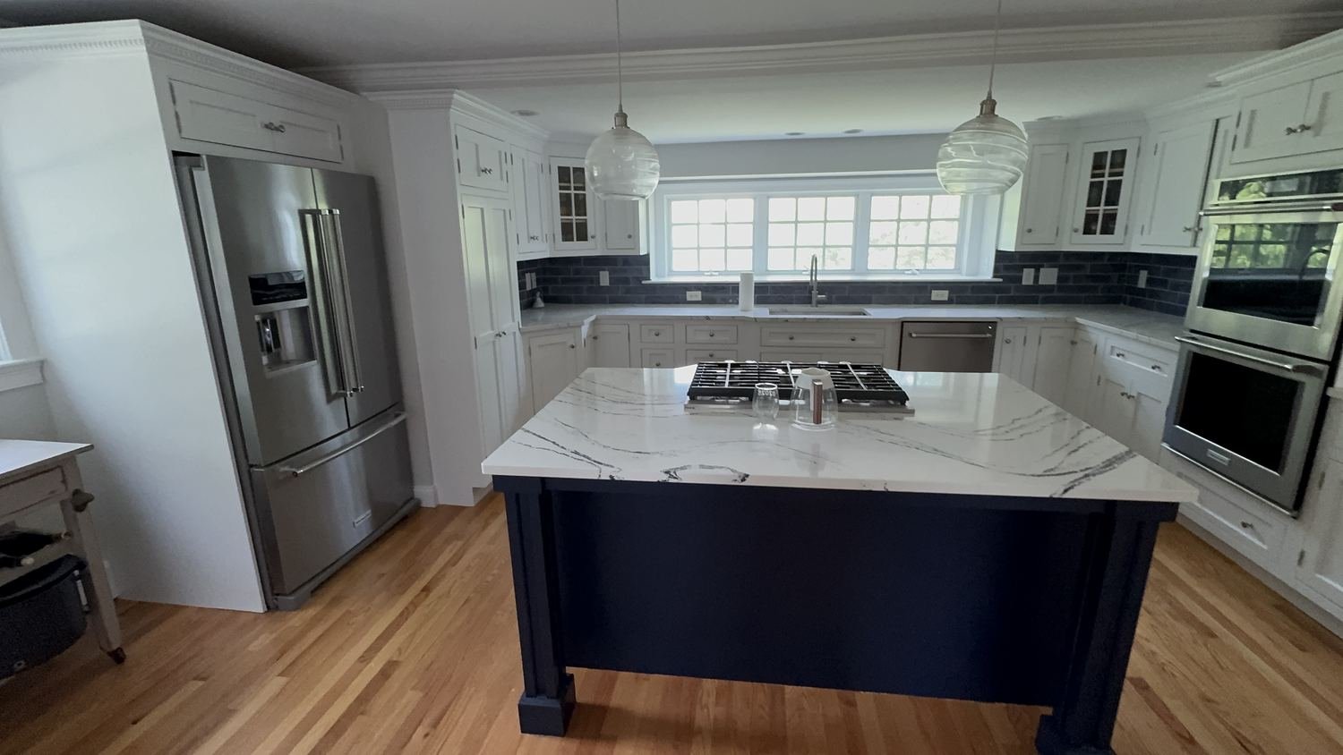 Custom kitchen with white shaker cabinets and navy blue island painted by Painting Now