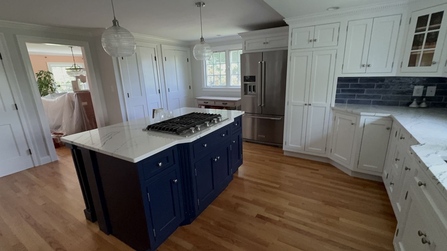 Custom kitchen front view with navy island, marble counters and white cabinets by Painting Now