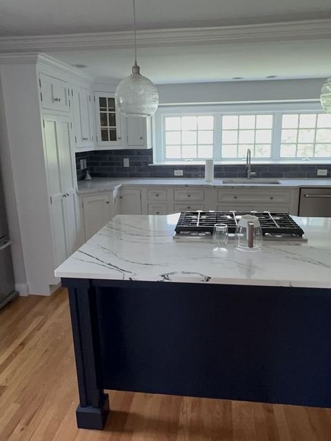 Kitchen cabinetry with marble counters and navy island