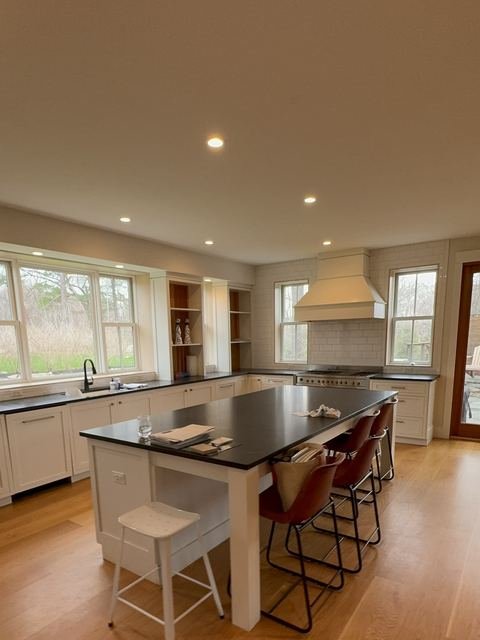 Kitchen with white cabinets, black island and plaster hood