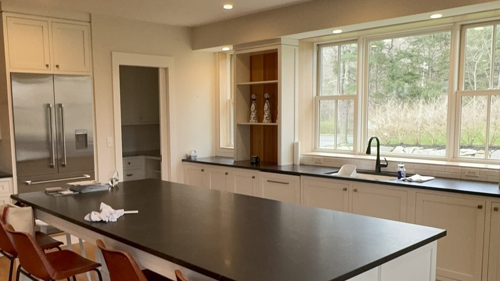 Wide open kitchen with white cabinetry, a dark island and custom painted window trim