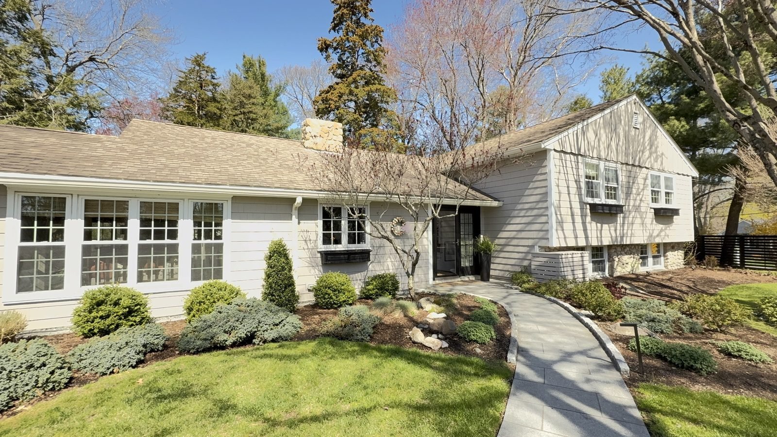 Shingle style ranch home with freshly painted white window trim and a black front door